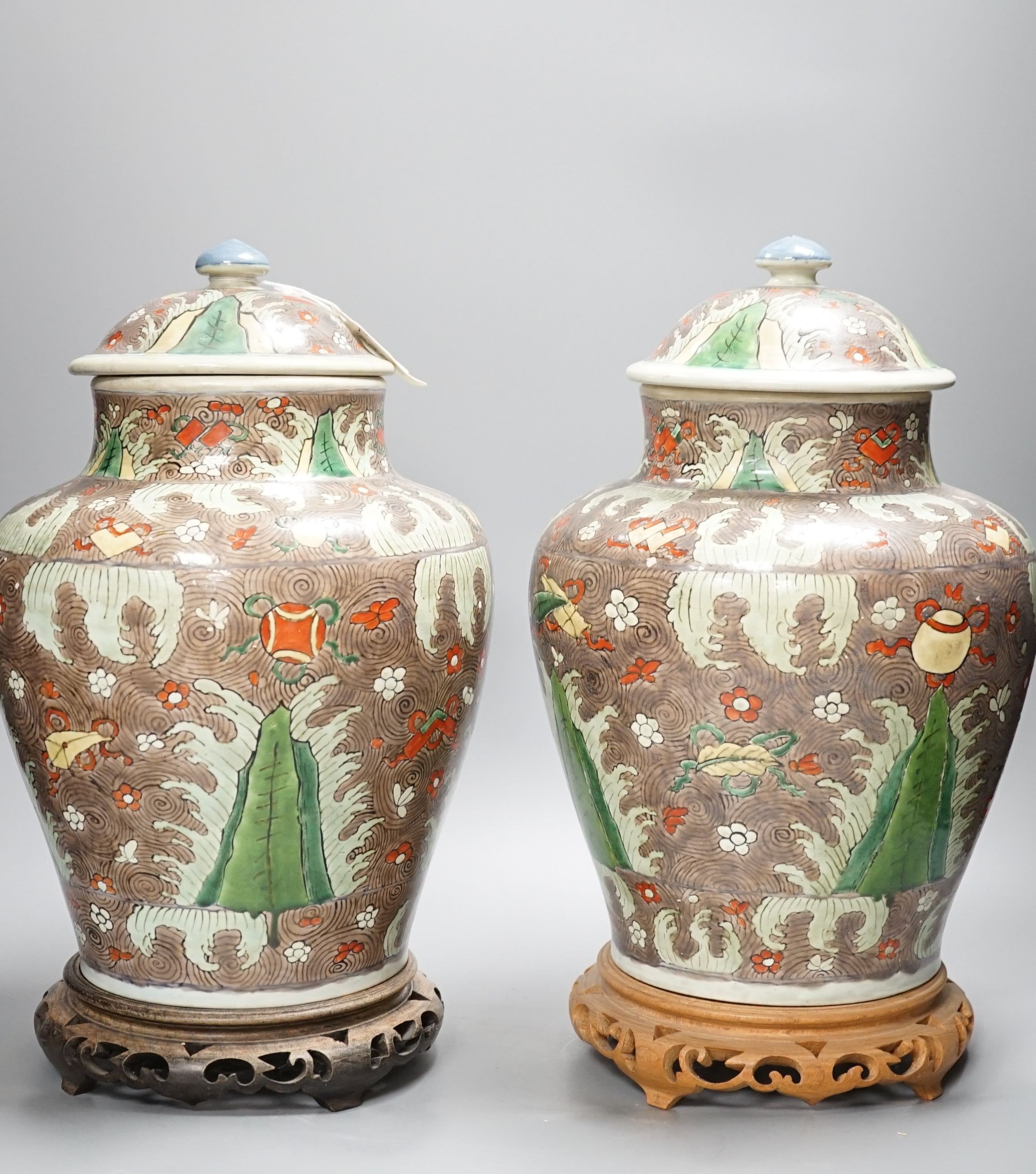 A pair of Chinese enamelled porcelain jars and covers, in Transitional style, 34cm high, wood stands